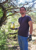 image de samuel aubert qui se tient debout à coté d'un arbre en tenant un bocal contenant de la résine